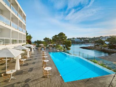 Piscine d'hôtel moderne avec eau bleue et vue sur la baie au coucher du soleil.