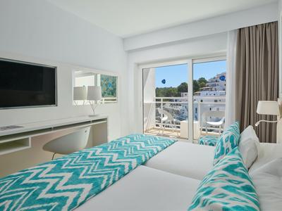 Chambre d'hôtel moderne avec deux lits, téléviseur à écran plat et vue sur une terrasse.