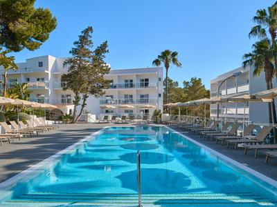 Piscine extérieure moderne avec transats et hôtel méditerranéen par temps ensoleillé.