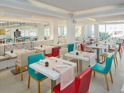 Restaurant d'hôtel lumineux et moderne avec des chaises colorées et des tables bien dressées.