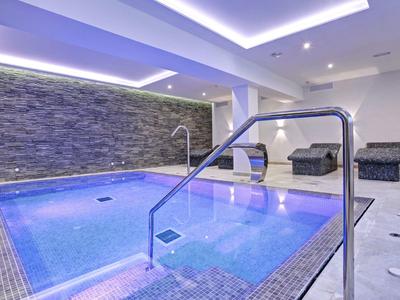Moderner Indoor-Pool mit steinverkleideter Wand und entspannenden Liegen