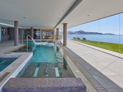 Piscina interna moderna con grandi pareti in vetro e vista mare in hotel.