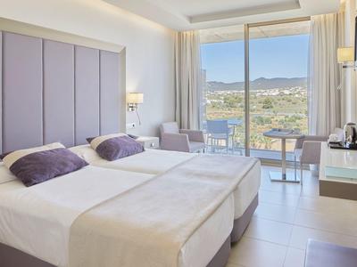 Camera d'hotel luminosa con due letti singoli e vista sul paesaggio.