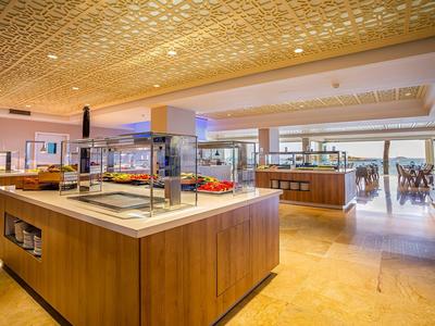 Sala colazione moderna con isole buffet e grandi finestre sullo sfondo.