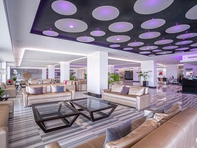 Area lounge moderna dell'hotel con comodi divani, tavoli in vetro e illuminazione indiretta.