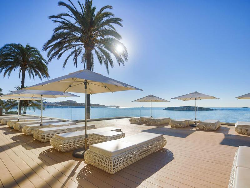 Lettini con ombrelloni sul mare sotto un cielo limpido e soleggiato.