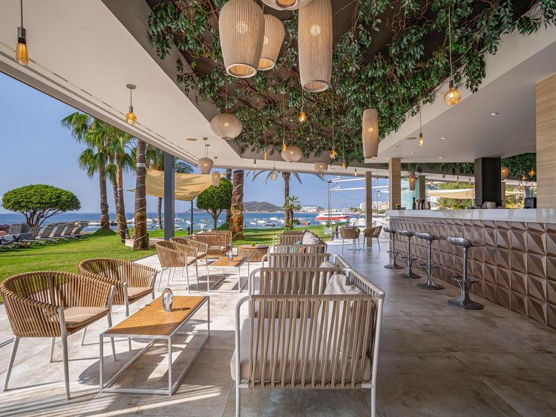 Area bar esterna moderna di un hotel con posti a sedere e vista mare.