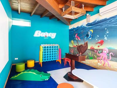 Kinderzimmer mit türkisfarbener Wand, Wandbild mit Meerestieren, Spielzeug und farbigen Hockern.