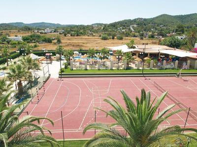 Czerwony kort tenisowy obok basenu z palmami i wzgórzami w tle