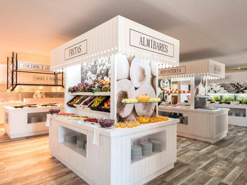 Heller moderner Supermarkt mit weißen Regalen, frischem Obst, Gemüse und Holzfußboden.