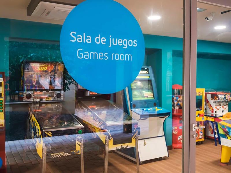 Spielezimmer mit klassischen Spielautomaten und Pinball-Automaten hinter Glastür.