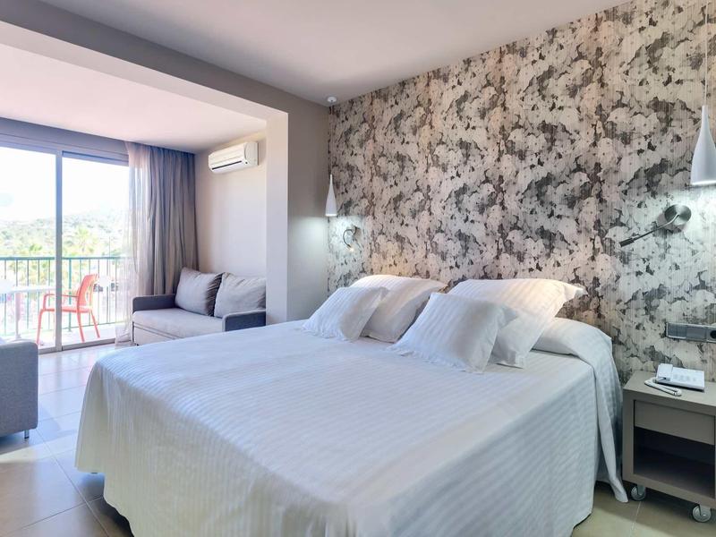 Modernes Schlafzimmer mit großer Betten, floralem Akzentwand und Balkon mit Sitzbereich.