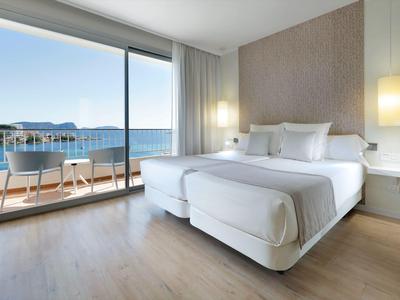 Modernes Hotelzimmer mit Doppelbett, Holzboden und Balkon mit Meerblick.