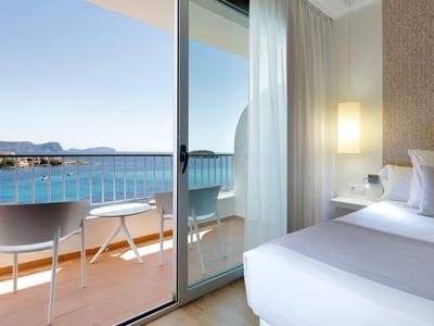 Hotelzimmer mit Blick auf Balkon und Meer, helle Einrichtung und entspannte Atmosphäre.
