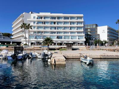 Modernes Hotel mit mehreren Etagen, Palmen und kleinen Booten am klaren Wasserhafen.