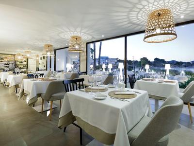 Elegantes Restaurant mit weiß gedeckten Tischen und Blick auf eine nächtliche Stadtlandschaft.