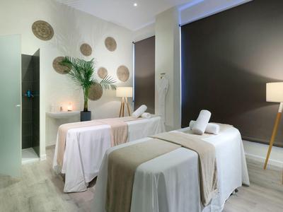 Gemütlicher Spa-Raum mit zwei Behandlungsliegen, sanfter Beleuchtung und beruhigender Dekoration.