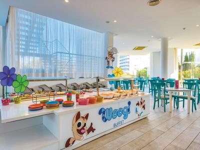 Hell beleuchteter Frühstücksbereich mit Buffet und farbenfrohen Tischdekorationen in modernem Stil.