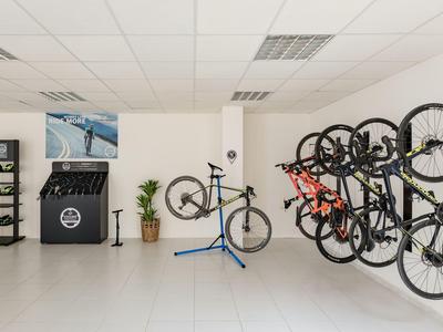 Moderner Fahrradreparaturraum mit mehreren aufhängten Fahrrädern und Werkzeugen.