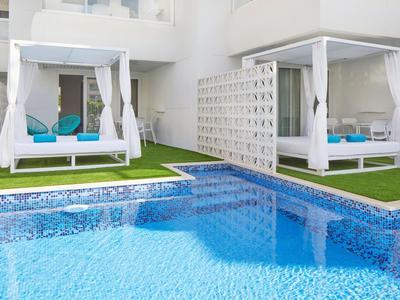 Zwei weiße Pavillons mit blauen Kissen neben einem klaren Pool auf Rasenfläche.