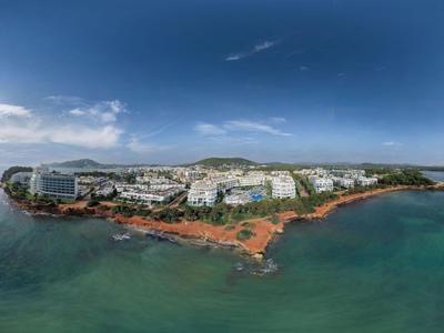 Luftaufnahme eines Hotels an der Küste mit türkisfarbenem Wasser und bewölktem Himmel