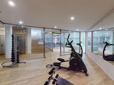 Moderner Fitnessraum mit Trainingsgeräten, Hanteln und Spiegelwand in einem Hotel.