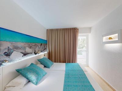 Modernes Hotelzimmer mit Doppelbett, türkisfarbenen Akzenten und Panoramabild über dem Kopfteil.