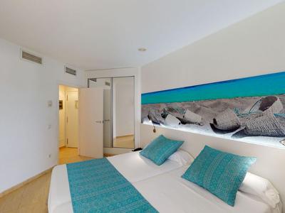 Modern eingerichtetes Hotelzimmer mit Doppelbett und türkisfarbenen Akzenten an Wand und Bett.