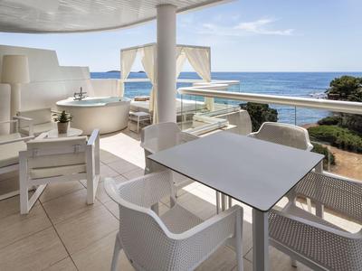 Modernes Hotelzimmerbalkon mit gemütlichen weißen Möbeln und Blick aufs Meer.