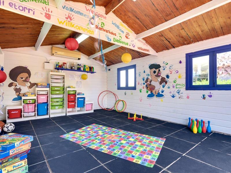 Bunter und gut organisierter Kinderspielraum mit Spielzeug, buntem Teppich und großen Wandbildern.