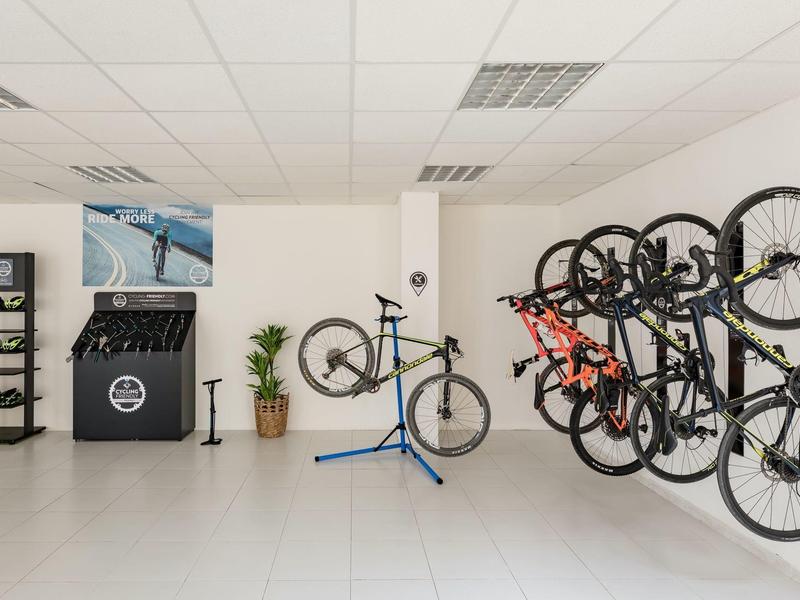 Moderner Fahrradladen mit mehreren Rennrädern an der Wand und einem in der Mitte auf Werkbank.