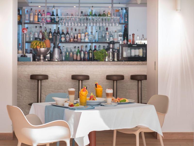 Strefa jadalni z nakrytym stołem i stołkami przy dobrze zaopatrzonym barze hotelowym.