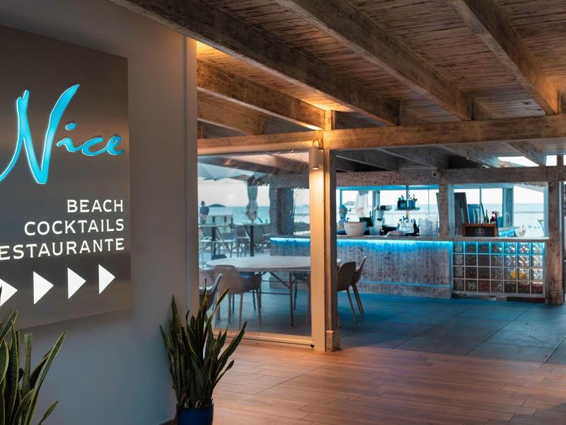 Nowoczesne wejście do restauracji na plaży z drewnianym sufitem i dużymi oknami.