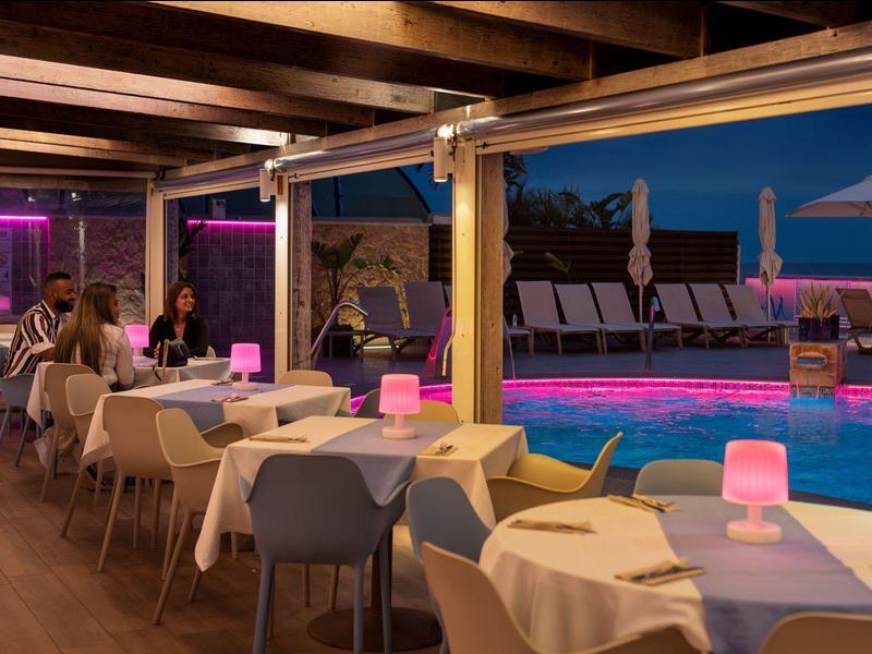 Wieczorny bar przy basenie z nakrytymi stołami i relaksującą atmosferą w hotelu.