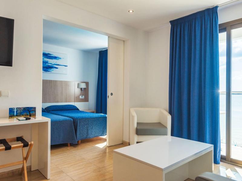 Nowoczesny pokój hotelowy z niebieskimi zasłonami i dostępem do balkonu.