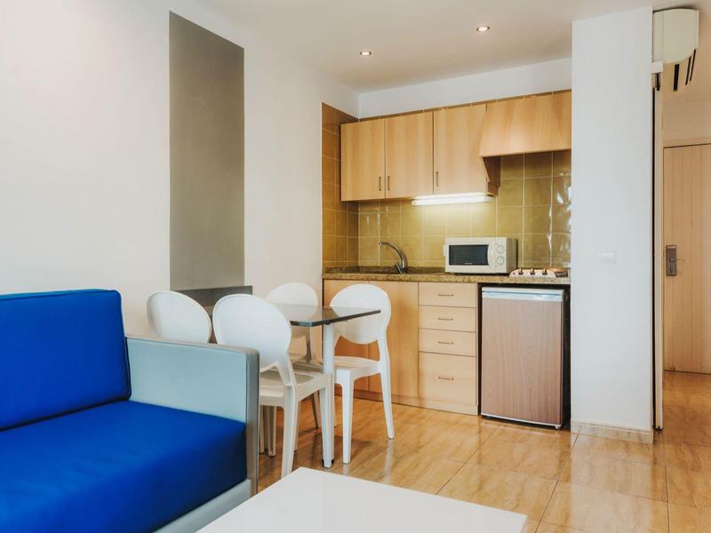 Nowoczesne mieszkanie z niebieską sofą i małą kuchnią z miejscem do jedzenia.