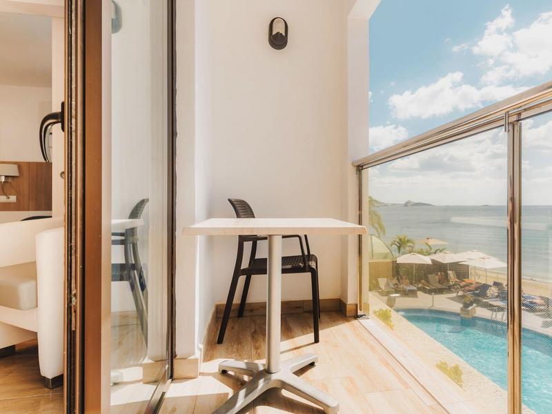 Balkon z stołem i krzesłami z widokiem na morze w słoneczny dzień.