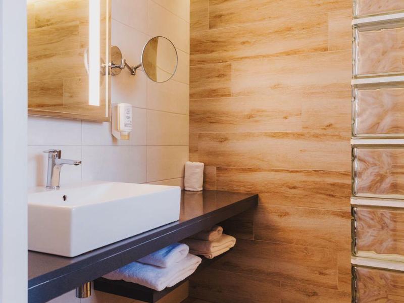 Nowoczesna łazienka z drewnianą okładziną, umywalką i podświetlanym lustrem.