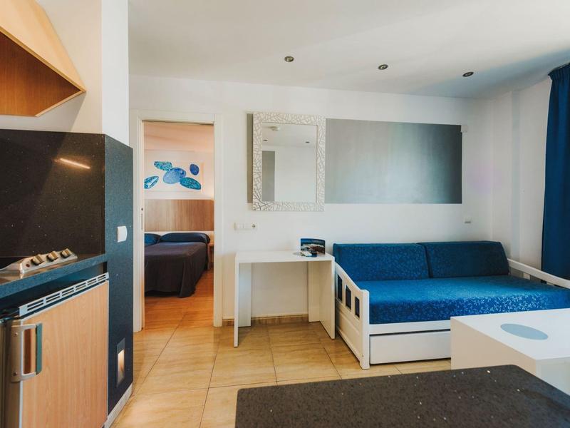 Nowoczesny pokój hotelowy z niebieską sofą, biurkiem i telewizorem.