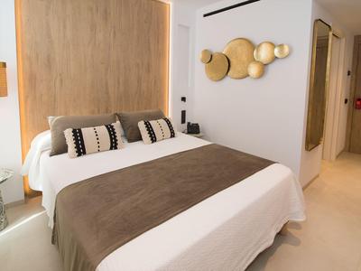 Modern hotel room with double bed, wooden wall panel, and decorative wall art.