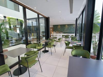 Modern lounge with green chairs and large windows, bright and spacious.