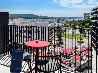 Balkon z stołem i dwoma krzesłami z widokiem na port i miasto pod niebieskim niebem.