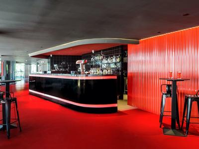 Nowoczesny bar hotelowy z czerwonym dywanem i czarnymi stołkami barowymi