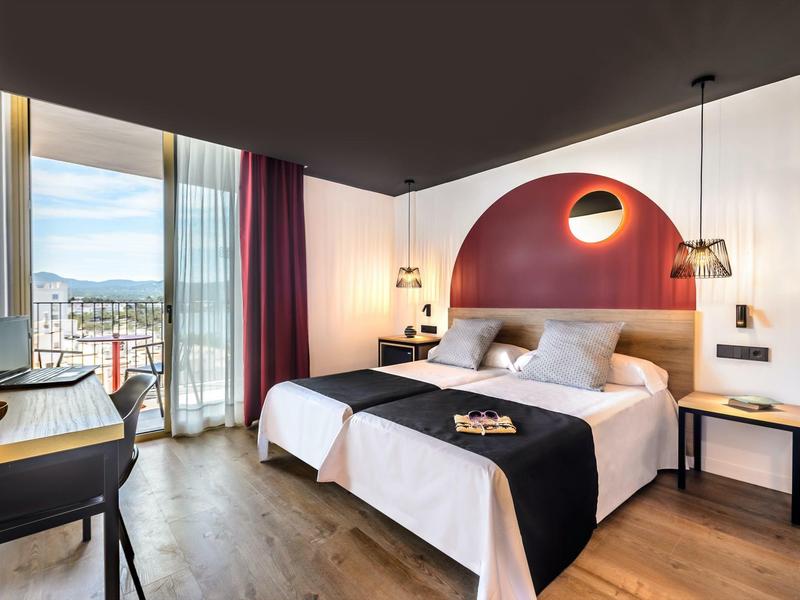 Nowoczesny pokój hotelowy z łóżkiem podwójnym, biurkiem, krzesłem i dużym oknem z widokiem.