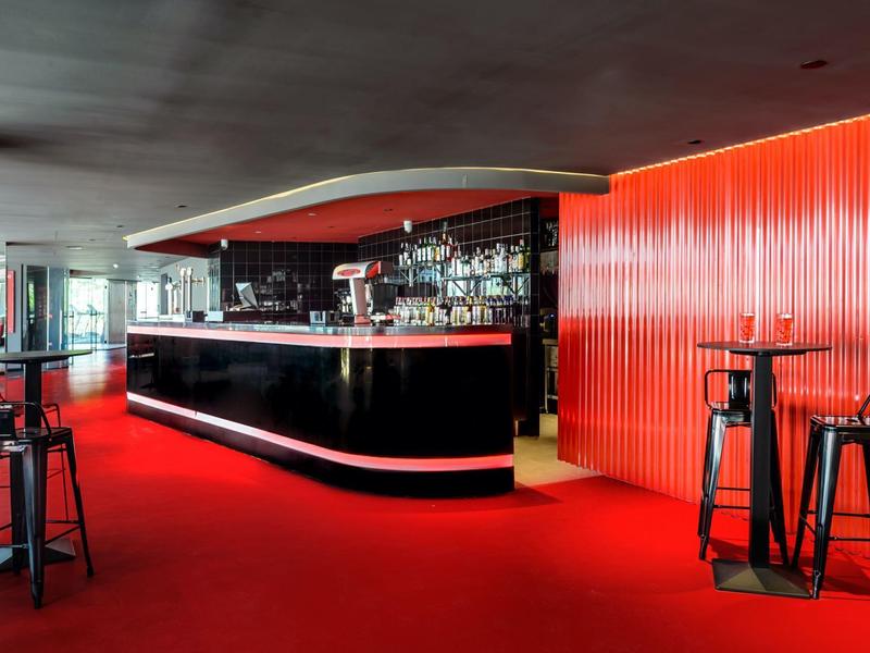 Nowoczesny bar hotelowy z czerwonym dywanem i czarnymi stołkami barowymi