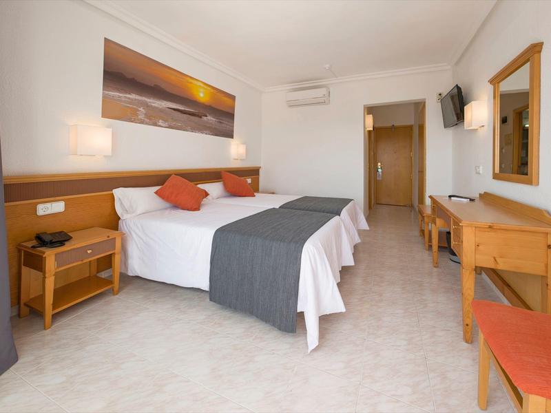 Licht ingerichte hotelkamer met tweepersoonsbed, houten meubels en wanddecoratie.