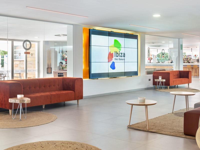 Lichte hotellounge met rode banken, ronde vloerkleden en tafels