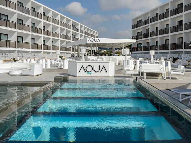 Modern hotelcomplex met blauw verlicht zwembad en luxe buitenruimte.