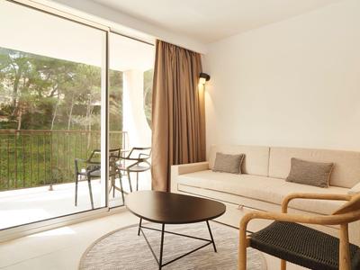 Apartamento luminoso con sofá, sillones, mesa de café redonda y vista a una terraza con sillas