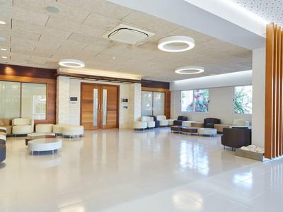 Área de vestíbulo de hotel luminosa y moderna con grupos de asientos y luces de techo.